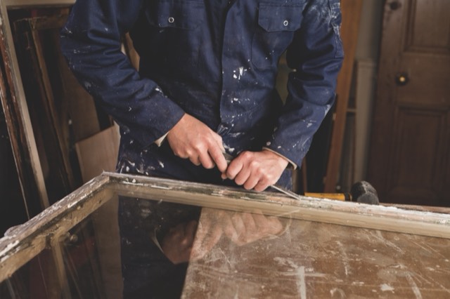 A joiner repairing an old sash window on the bench in a London workshop